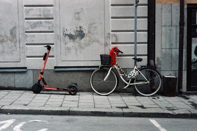 red and black bicycle with training wheels beside white wall